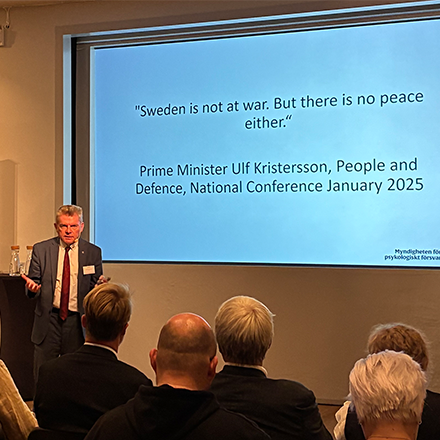 Magnus Hjort f&ouml;rel&auml;ser, p&aring; tavlan bakom st&aring;r citatet fr&aring;n Sveriges statsminister "Sweden is not at war. But there is no peace either".